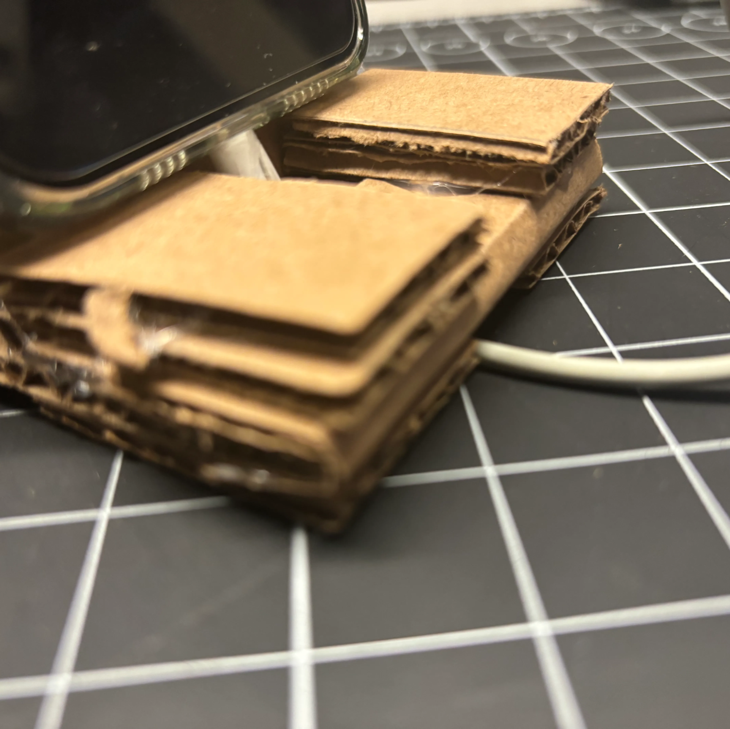 The third prototype added more cardboard to the bottom to allow the phone stand to rest on the table without the wire in the way.